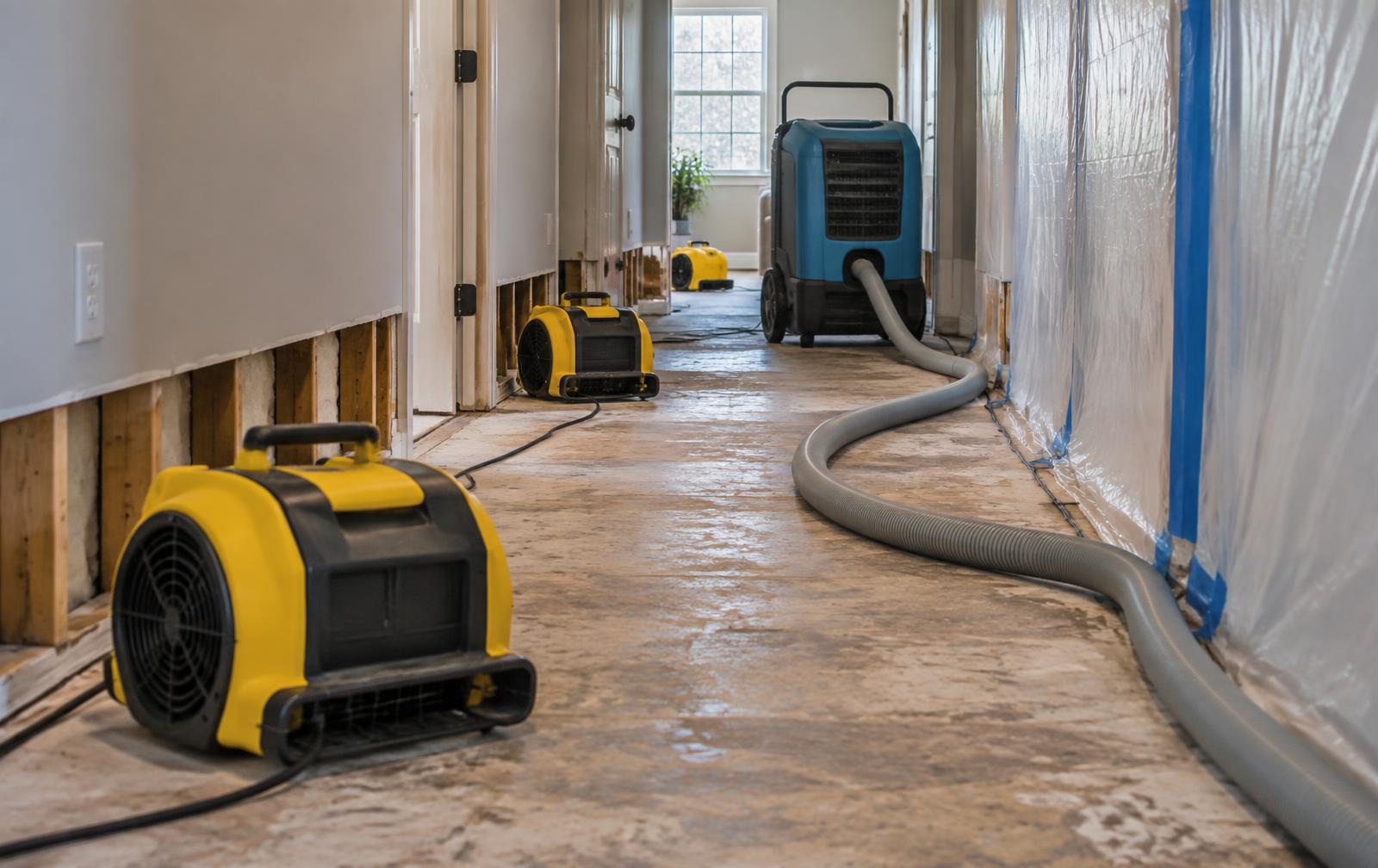 Air movers and a commercial dehumidifier drying a hallway after residential water damage